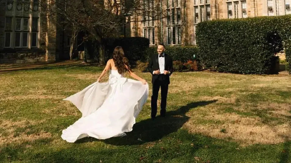 Two people in formal attire standing in front of a large tower building.