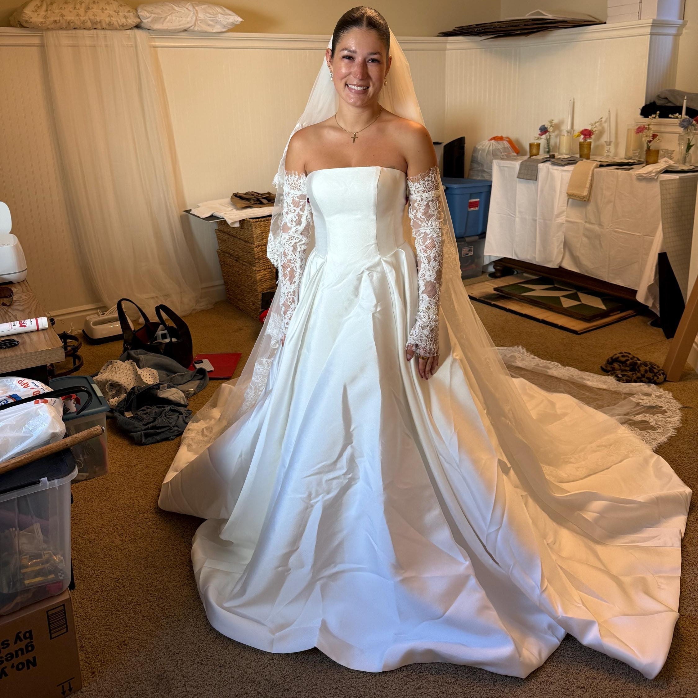 Woman in a white wedding dress standing in a room with various items and furniture.